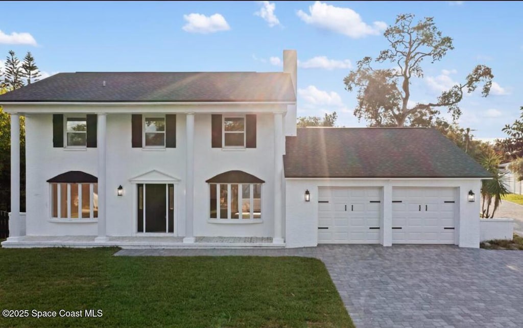 2511 Indian River Dr, Cocoa, FL 32922 - neoclassical / greek revival house with an attached garage, driveway, a front lawn, and stucco siding