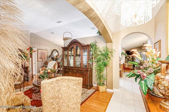 2595 Diane Ave SE, Palm Bay, FL 32909 - entrance foyer featuring arched walkways, a chandelier, a textured ceiling, light tile patterned flooring, and lofted ceiling