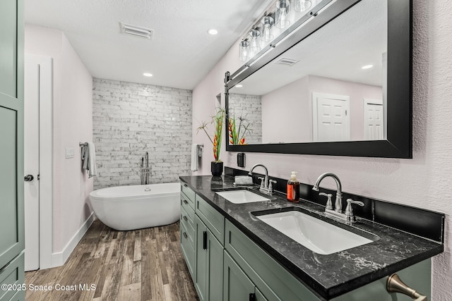 1379 Rose Ct, Melbourne, FL 32935 - bathroom with double vanity, wood finished floors, a soaking tub, a textured ceiling, and recessed lighting