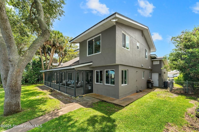 1379 Rose Ct, Melbourne, FL 32935 - rear view of house with stucco siding, a sunroom, and a gate