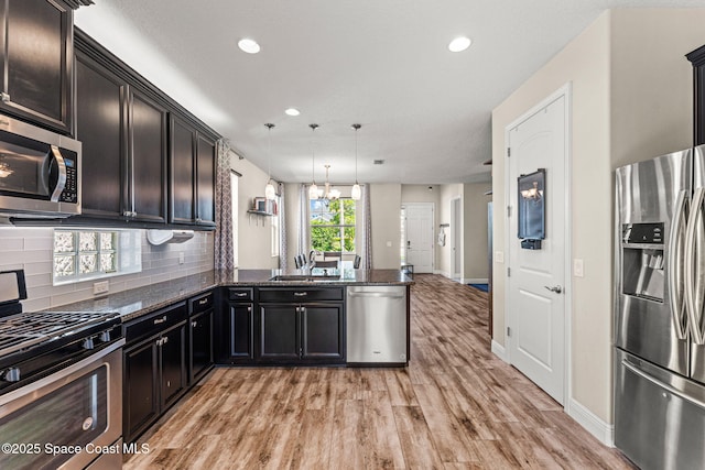 2920 Casterton Dr, Melbourne, FL 32940 - kitchen featuring stainless steel appliances, light wood-style flooring, dark stone counters, a peninsula, and recessed lighting