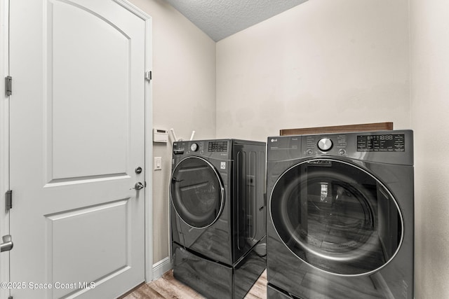 2920 Casterton Dr, Melbourne, FL 32940 - laundry room featuring washing machine and clothes dryer, a textured ceiling, and wood finished floors
