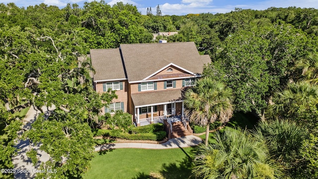 1407 Rockledge Dr, Rockledge, FL 32955 - view of front of property with brick siding, covered porch, a wooded view, and a front lawn