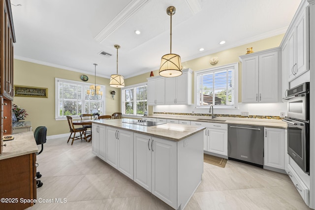 1407 Rockledge Dr, Rockledge, FL 32955 - kitchen featuring appliances with stainless steel finishes, ornamental molding, a center island, white cabinets, and hanging light fixtures