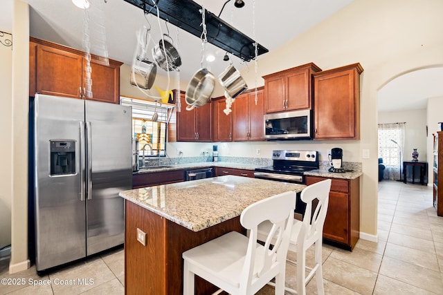 980 Dillard Dr SE, Palm Bay, FL 32909 - kitchen with stainless steel appliances, light tile patterned flooring, arched walkways, a center island, and vaulted ceiling