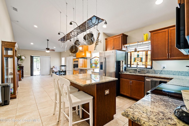 980 Dillard Dr SE, Palm Bay, FL 32909 - kitchen featuring a center island, light tile patterned floors, ceiling fan, light stone counters, and stainless steel refrigerator with ice dispenser