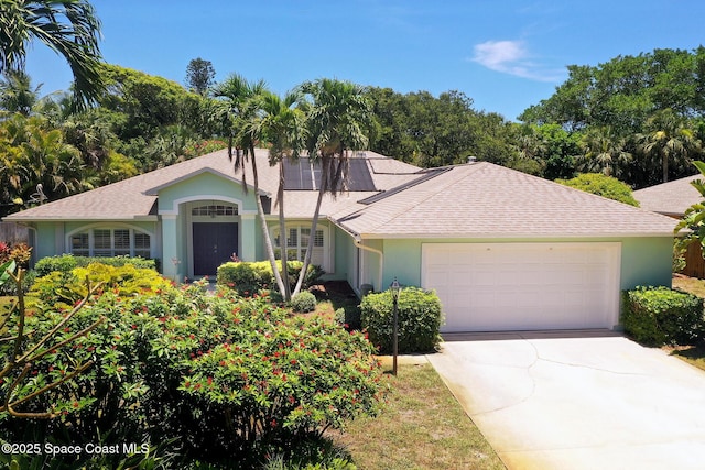 112 Carmen St, Melbourne Beach, FL 32951 - view of front facade with stucco siding, a garage, roof with shingles, roof mounted solar panels, and driveway