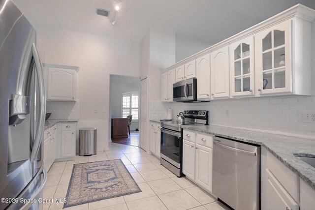 112 Carmen St, Melbourne Beach, FL 32951 - kitchen with stainless steel appliances, white cabinets, tasteful backsplash, and glass insert cabinets