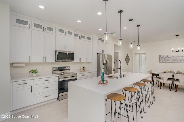 942 Toluca St SE Unit 1, Palm Bay, FL 32909 - kitchen featuring appliances with stainless steel finishes, an island with sink, a breakfast bar, white cabinets, and light countertops