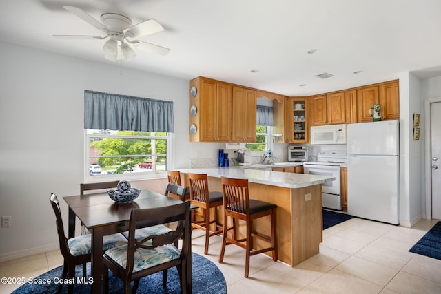 61 Woodland Dr Unit 201, Vero Beach, FL 32962 - kitchen with white appliances, a peninsula, brown cabinets, glass insert cabinets, and light countertops