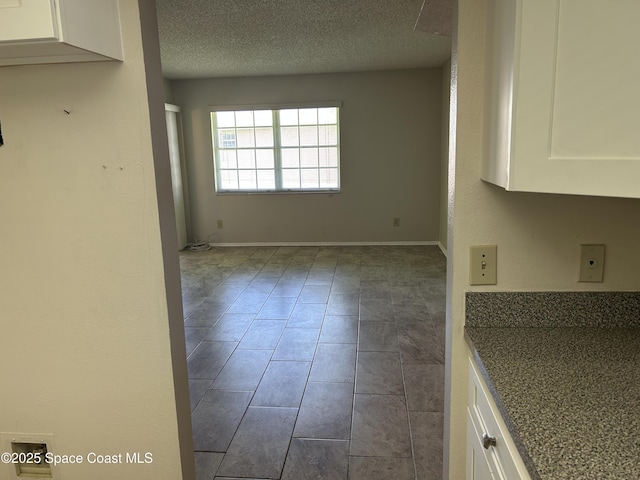 951 Sonesta Ave NE Unit 204, Palm Bay, FL 32905 - unfurnished dining area featuring a textured ceiling and dark tile patterned flooring