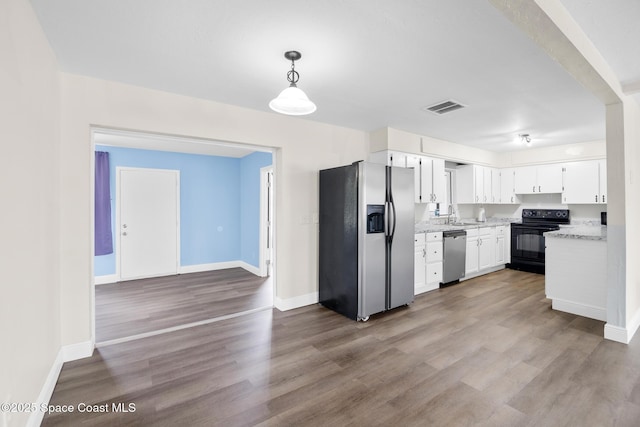 1421 Degroodt Rd SW, Palm Bay, FL 32908 - kitchen with appliances with stainless steel finishes, wood finished floors, white cabinetry, hanging light fixtures, and light stone counters