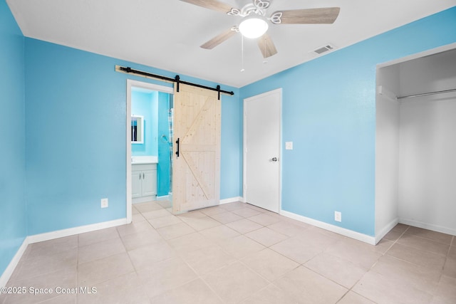 1421 Degroodt Rd SW, Palm Bay, FL 32908 - unfurnished bedroom featuring a barn door, light tile patterned floors, and a ceiling fan