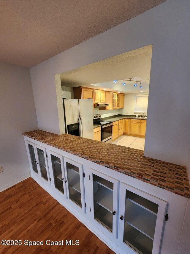 5807 N Atlantic Ave Unit 322, Cape Canaveral, FL 32920 - kitchen with electric range, refrigerator with ice dispenser, glass insert cabinets, light wood finished floors, and a textured ceiling