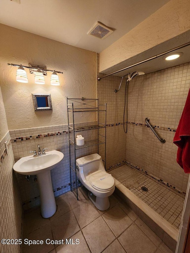 5807 N Atlantic Ave Unit 322, Cape Canaveral, FL 32920 - full bath with a textured wall, a shower stall, tile walls, tile patterned floors, and wainscoting