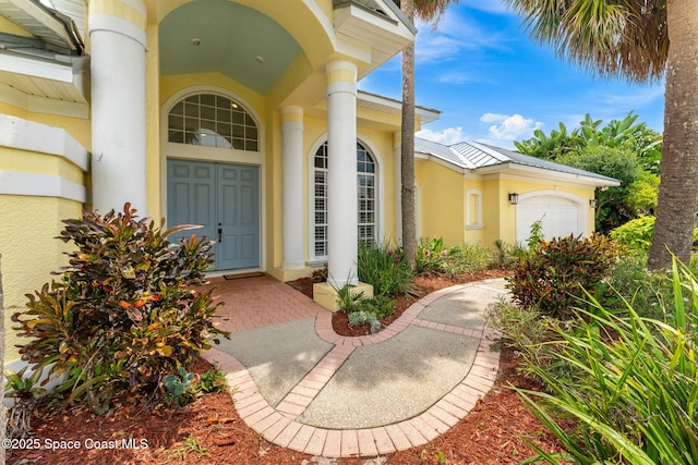 174 Martesia Way, Indian Harbour Beach, FL 32937 - doorway to property featuring stucco siding, a garage, and a metal roof