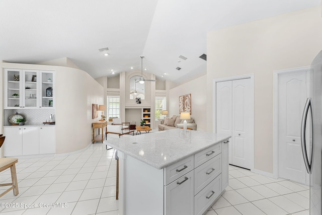 174 Martesia Way, Indian Harbour Beach, FL 32937 - kitchen with light tile patterned floors, fridge, glass insert cabinets, backsplash, and light stone countertops