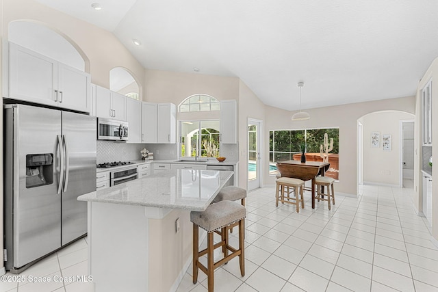 174 Martesia Way, Indian Harbour Beach, FL 32937 - kitchen with appliances with stainless steel finishes, vaulted ceiling, backsplash, light tile patterned floors, and a breakfast bar area