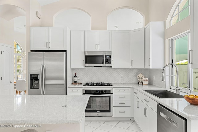 174 Martesia Way, Indian Harbour Beach, FL 32937 - kitchen featuring appliances with stainless steel finishes, decorative backsplash, light stone countertops, light tile patterned floors, and white cabinets