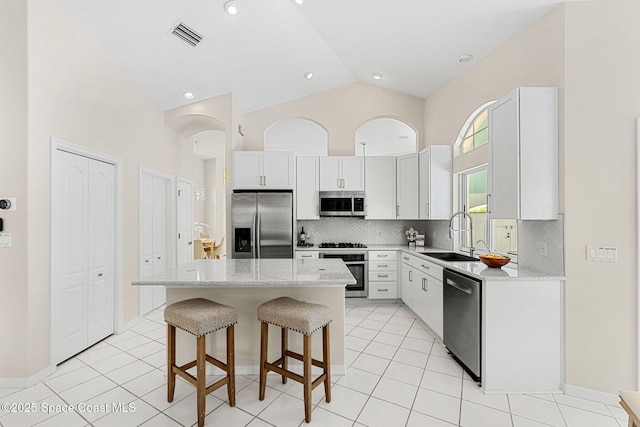174 Martesia Way, Indian Harbour Beach, FL 32937 - kitchen featuring appliances with stainless steel finishes, high vaulted ceiling, a center island, a kitchen bar, and tasteful backsplash