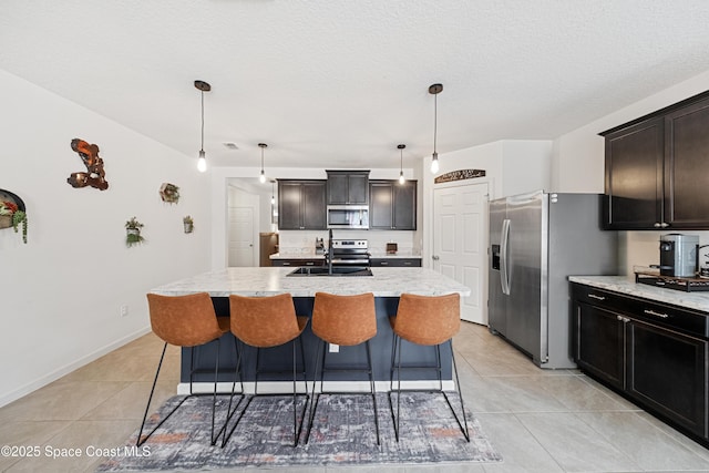 5071 Talbot Blvd, Cocoa, FL 32926 - kitchen featuring appliances with stainless steel finishes, light tile patterned floors, light stone counters, a kitchen bar, and a kitchen island with sink