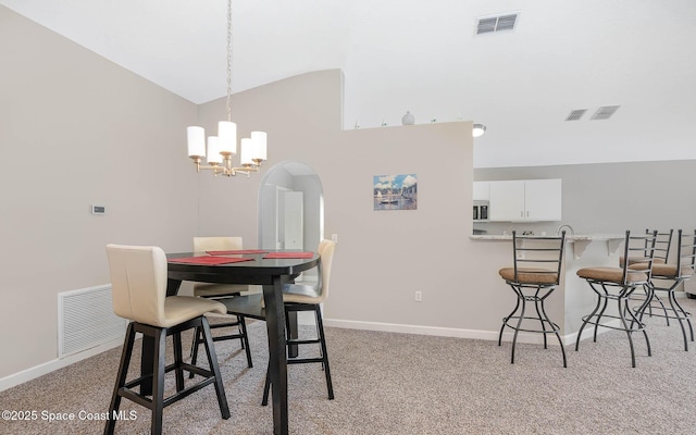 2221 Spring Creek Cir, Palm Bay, FL 32905 - dining space with a chandelier, vaulted ceiling, light carpet, and arched walkways