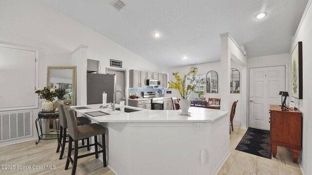 160 Eureka Ave NE, Palm Bay, FL 32907 - kitchen with stainless steel appliances, light countertops, a breakfast bar area, lofted ceiling, and recessed lighting