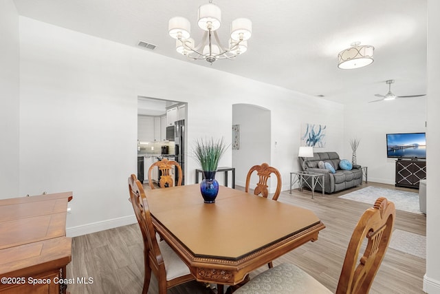 1014 Pelican Ln, Rockledge, FL 32955 - dining room with arched walkways, light wood-style flooring, a chandelier, and a ceiling fan