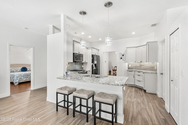 1014 Pelican Ln, Rockledge, FL 32955 - kitchen featuring appliances with stainless steel finishes, a peninsula, a breakfast bar area, tasteful backsplash, and light wood-style floors
