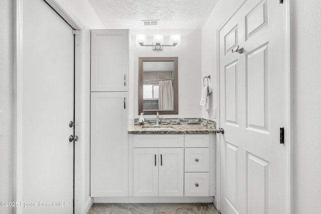 1014 Pelican Ln, Rockledge, FL 32955 - bathroom with a textured ceiling, vanity, and marble look tiles