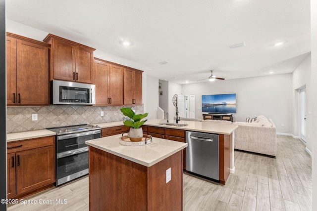 3550 Salt Marsh Cir, West Melbourne, FL 32904 - kitchen with appliances with stainless steel finishes, open floor plan, a peninsula, light wood-style floors, and tasteful backsplash