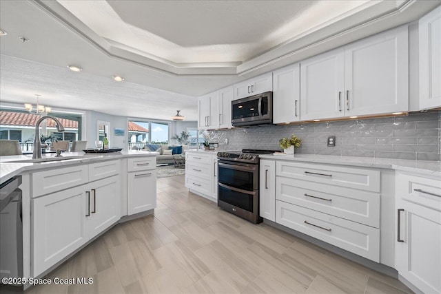 8954 Puerto Del Rio Dr Unit 1503, Cape Canaveral, FL 32920 - kitchen with appliances with stainless steel finishes, white cabinetry, tasteful backsplash, a chandelier, and light stone counters