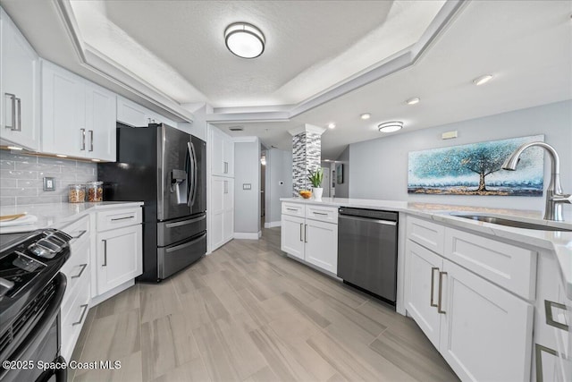 8954 Puerto Del Rio Dr Unit 1503, Cape Canaveral, FL 32920 - kitchen featuring appliances with stainless steel finishes, a raised ceiling, white cabinets, decorative backsplash, and ornate columns