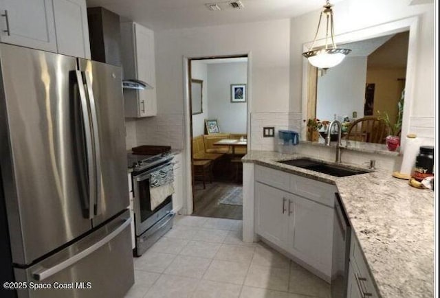 698 Awin Ct SE, Palm Bay, FL 32909 - kitchen featuring appliances with stainless steel finishes, wall chimney exhaust hood, light stone counters, light tile patterned floors, and decorative light fixtures