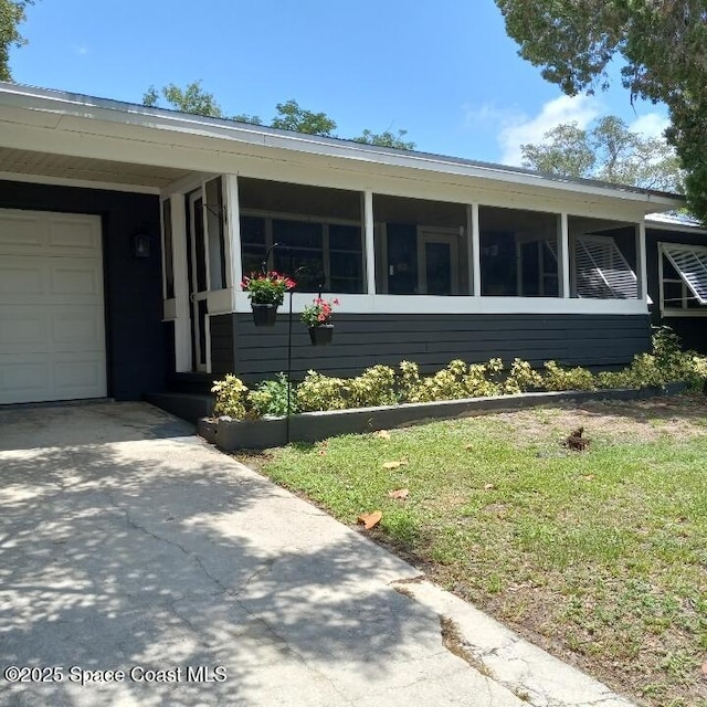 406 Mcleod Dr, Cocoa, FL 32922 - view of side of property with an attached garage, concrete driveway, and a sunroom