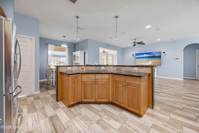 2542 Woodfield Cir, Melbourne, FL 32904 - kitchen featuring freestanding refrigerator, a ceiling fan, arched walkways, dark stone counters, and decorative light fixtures