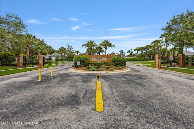 2542 Woodfield Cir, Melbourne, FL 32904 - view of asphalt street with traffic signs, a gate, a gated entry, and curbs