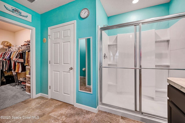 6586 Split Rail Ln, Cocoa, FL 32927 - bathroom featuring a stall shower, a walk in closet, vanity, and a textured ceiling