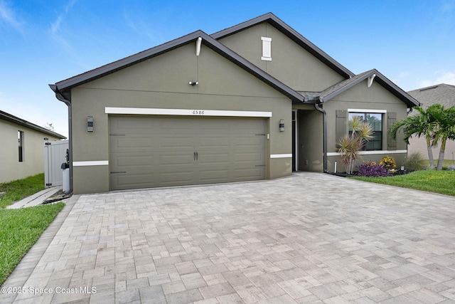 6586 Split Rail Ln, Cocoa, FL 32927 - view of front of home featuring stucco siding, decorative driveway, and an attached garage