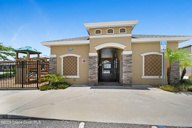6586 Split Rail Ln, Cocoa, FL 32927 - view of exterior entry with stucco siding, stone siding, and a gate