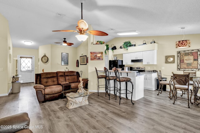 5505 95th St, Sebastian, FL 32958 - living room featuring lofted ceiling, light wood-type flooring, ceiling fan, and a textured ceiling