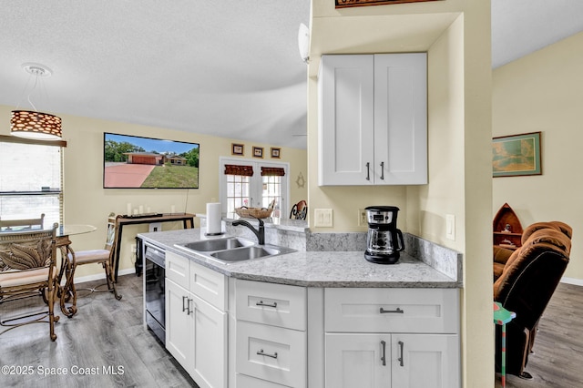 5505 95th St, Sebastian, FL 32958 - kitchen with light wood-type flooring, white cabinetry, light stone countertops, pendant lighting, and a peninsula