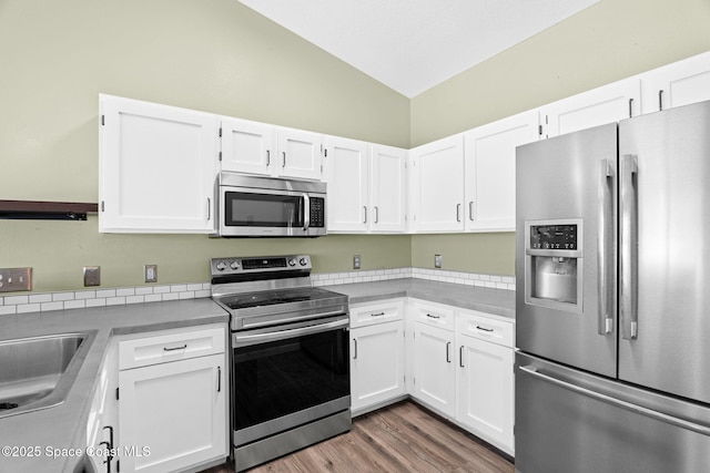 120 Norwood Ave Unit 120, Satellite Beach, FL 32937 - kitchen featuring appliances with stainless steel finishes, vaulted ceiling, white cabinetry, light countertops, and wood finished floors