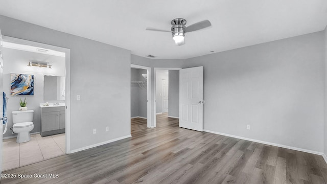1880 Long Iron Dr Unit 1322, Rockledge, FL 32955 - unfurnished bedroom featuring a walk in closet, wood finished floors, a closet, ensuite bath, and a ceiling fan