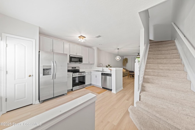 1311 Hampton Park Ln, Melbourne, FL 32940 - kitchen featuring stainless steel appliances, a peninsula, light wood-type flooring, light countertops, and pendant lighting
