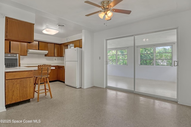 955 Samar Rd, Cocoa Beach, FL 32931 - kitchen with freestanding refrigerator, under cabinet range hood, brown cabinetry, light countertops, and stainless steel oven