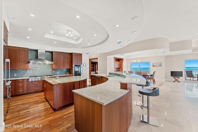 2375 S Atlantic Ave Unit 601, Cocoa Beach, FL 32931 - kitchen with wall chimney range hood, a spacious island, modern cabinets, a raised ceiling, and recessed lighting