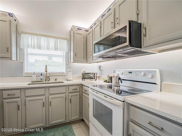 57 Woodland Dr Unit 201, Vero Beach, FL 32962 - kitchen with white electric range, stainless steel microwave, light tile patterned floors, and gray cabinets