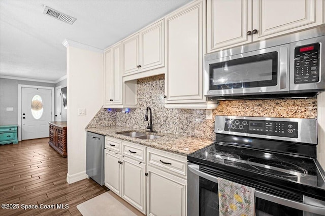 13 Lee St, Cocoa, FL 32926 - kitchen with appliances with stainless steel finishes, decorative backsplash, dark wood-style floors, ornamental molding, and light stone countertops
