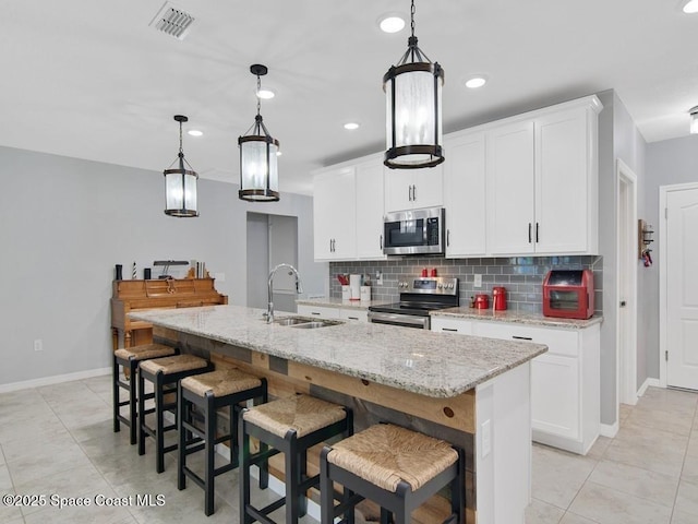 9025 106th Ave, Vero Beach, FL 32967 - kitchen with appliances with stainless steel finishes, backsplash, a center island with sink, light tile patterned flooring, and recessed lighting